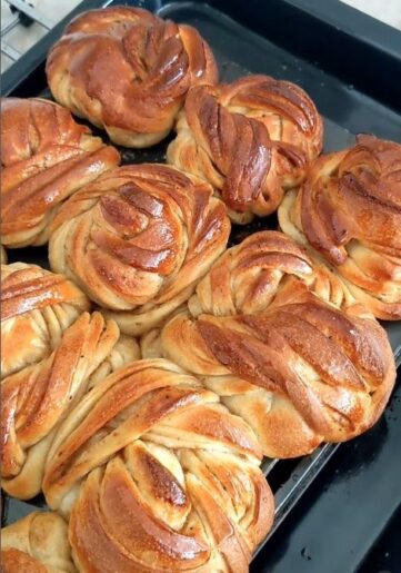 Nybakade, gyllenbruna bullar med snurrade degmönster på en plåt
