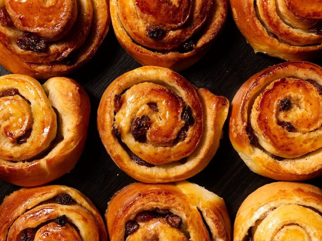 Nybakade gyllenbruna bullar med russin, tätt arrangerade på ett mörkt fat